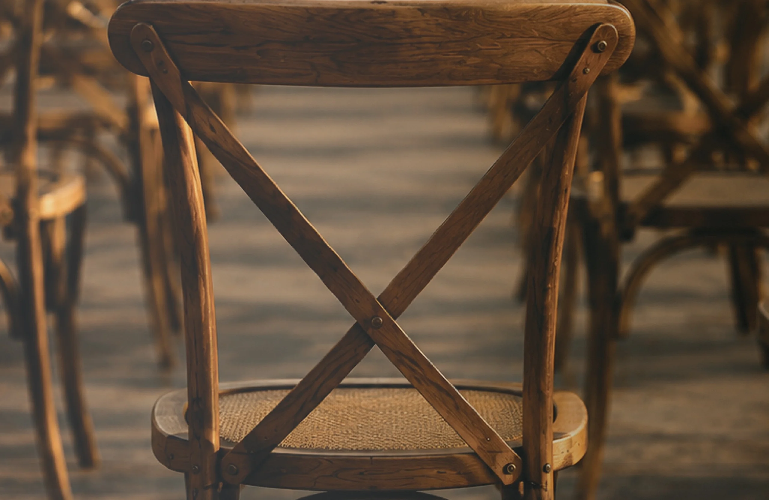 The back of a wooden cross-back chair waiting at the table